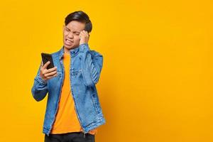 geschokte aziatische jonge man die naar bericht op smartphone kijkt foto