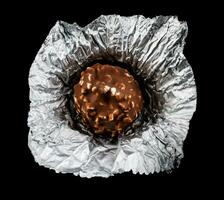 onverpakt chocola snoep in folie Aan een zwart achtergrond. foto