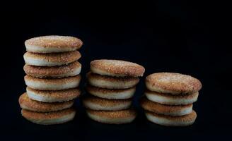 mooi ronde koekjes Aan een zwart achtergrond. een weinig koekjes. drie koekje torens. foto