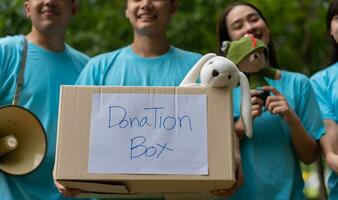 gelukkig jong Aziatisch studenten verschillend vrijwilligers houden schenken doos en speelgoed voor liefdadigheid naar delen kinderen en weeshuizen, een liefdadigheid voor duurzaamheid. vrijwilliger werk levensstijl en sociaal samenwerking foto