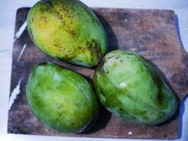 drie arumanis mango's Aan een houten snijdend bord foto