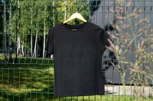 een mockup van een zwart t-shirt met kort mouwen is hangende Aan een hanger foto
