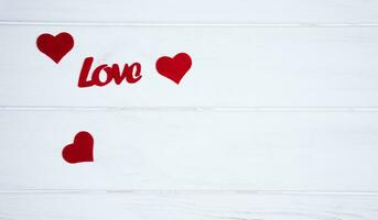 woord liefde en rood harten Aan wit houten achtergrond. Valentijnsdag dag vakantie concept. spandoek. top visie. plat leggen. plaats voor uw tekst. foto