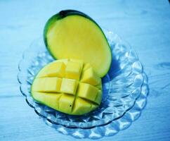 mango's gesneden besnoeiing naar kubussen Aan een glas bord , top visie foto