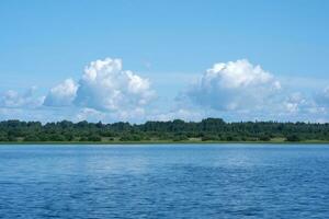 waterlandschap, bebost kust van de meer, visie van de water Aan een zonnig dag foto