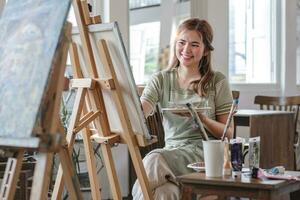 jong vrouw artiest werken Aan abstract acryl schilderij Aan canvas in kunst schilderij studio. foto