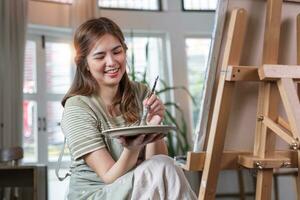 jong vrouw artiest werken Aan abstract acryl schilderij Aan canvas in kunst schilderij studio. foto