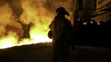 metallurg arbeider in beschermend uniform Bij de staal fabriek controlerend heet gesmolten metaal gieten werkwijze. Mens werken in zwaar industrie. foto