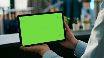 winkel arbeider analyseren digitaal apparaat met chroma sleutel groen scherm bespotten omhoog Scherm, werken in kleding op te slaan. Aziatisch arbeider Holding tablet computer in boodschappen doen winkelcentrum. technologie concept foto