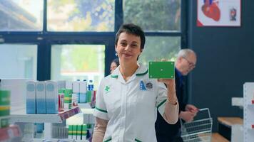 portret van glimlachen drogist in apotheek Holding mockup verpakt farmaceutisch Product. vriendelijk gezondheidszorg specialist klaar naar voorzien geneeskrachtig Diensten naar klanten, Holding geïsoleerd pillen doos foto