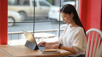 freelance dienstmeisje gebruikt een laptop om een nieuw project te doen om klanten in een coffeeshop te presenteren.