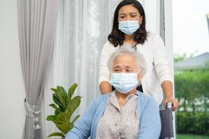 help aziatische senior of oudere oude dame vrouw zittend op een rolstoel en het dragen van een gezichtsmasker ter bescherming van de veiligheidsinfectie covid-19 coronavirus. foto