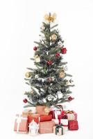 versierde kerstboom met cadeau verpakt presenteert geïsoleerd op een witte achtergrond. foto