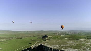 heet lucht ballonnen in de lucht over- de veld- in de platteland. schot. antenne visie van aerostaten vlieg bovenstaand de zomer weide. foto