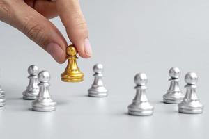 hand met gouden schaakpionstukken of leiderzakenman met zilveren mannen. overwinning, leiderschap, zakelijk succes, team, werving en teamwork concept foto