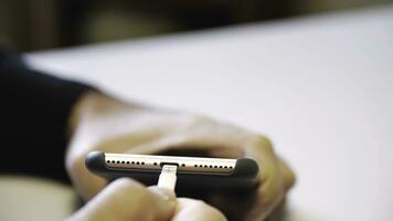 dichtbij omhoog van hand- invoegen een USB kabel oplader in een mobiel telefoon. media. dichtbij omhoog mans hand- invoegen een oplader in een slim telefoon door een bliksem kabel. foto