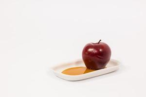 Rode appel op witte plaat met honing geïsoleerd op een witte achtergrond foto