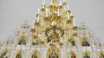 christen orthodox kerk interieur in wit en gouden kleuren. video. kroonluchter met kunstmatig kaarsen in de tempel met iconostase. foto