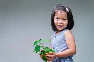 kind en kleine boom in de natuur kokosnoot pot. lieve glimlach meisje. wereld redden. milieu Dag. groeiende boom. lente seizoen. omgeving redden. wereld dag. dag van de Aarde. kind bedrijf jonge groene boom. foto