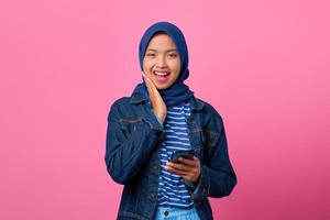 portret van glimlachende jonge aziatische vrouw die mobiele telefoon met hand op haar wangen houdt