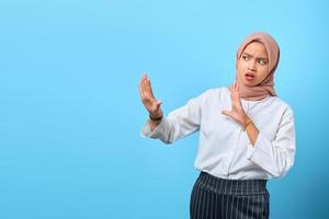 portret van nerveuze angstige jonge aziatische vrouw stop niet bewegen gebaar over blauwe achtergrond