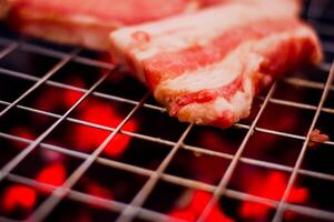 grillen varkensvlees Aan roestvrij staal rooster met vlammen Aan zwart achtergrond, voedsel en keuken concept. brandend varkensvlees Aan een houtskool grillen. foto