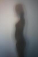 kant visie van vrouw silhouet achter berijpt glas foto