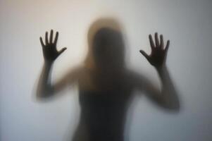 vrouw silhouet met verheven handen achter berijpt glas foto