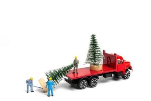 miniatuurmensen, arbeider die kerstboom op witte achtergrond voorbereiden foto