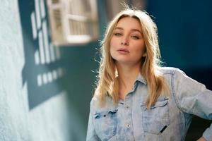 portret van een blonde vrouw met een denim shirt dat op straat staat. foto