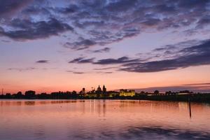 middeleeuws kasteel en skyline van de stad verlicht bij zonsondergang foto