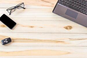een laptop, cel telefoon, en bril Aan een houten tafel foto