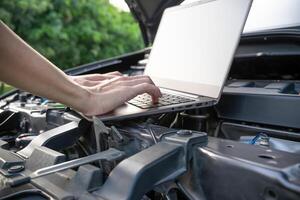 dichtbij omhoog hand- technicus gebruik computer analyseren auto problemen de parkeren veel Aan de kant van de weg foto