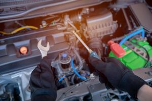 technicus is gebruik makend van een moersleutel en schroevedraaier voor reparatie auto in auto onderhoud en onderhoud concept foto