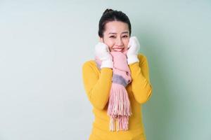 mooie jonge aziatische vrouw die sweater op groene achtergrond draagt foto