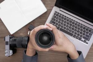 dichtbij omhoog camera lens in hand- een Mens en fotografie uitrusting Aan wijnoogst hout tafel foto werk concept