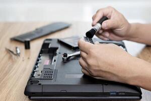 computer geletterdheid reparatie mannen Holding geheugen van laptop en gebruik struik schoonmaak met computer reparatie en gereedschap uitrusting Aan tafel foto