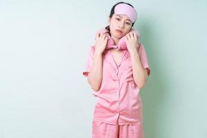 jonge aziatische vrouw die pyjama's op groene achtergrond draagt foto