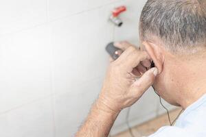 huis onderhoud concept een Mens gebruik water lekken controleren machine controleren lekken van water pijp in beton muur foto