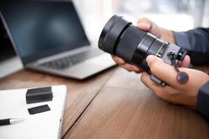 een Mens verandering camera lens en camera en fotografie uitrusting Aan tafel foto