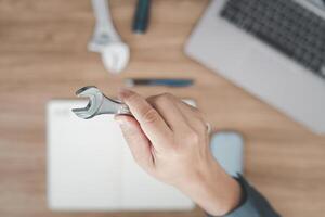 top visie foto de technicus houden een moersleutel in hand- en gebruikt een computer laptop naar analyseren de gebroken van auto in onderhoud kamer concept