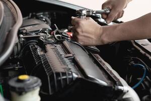 detailopname moersleutel in hand- mannetje monteur reparaties auto in garage. auto onderhoud en auto onderhoud garage concept foto