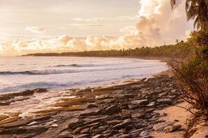 warm zonsopkomst of zonsondergang Bij tropisch kustlijn met oceaan en golven foto