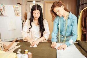 naaisters maken schetsen, patroon Aan kleding stof. atelier, maatwerk van individu kleren, klein bedrijf foto