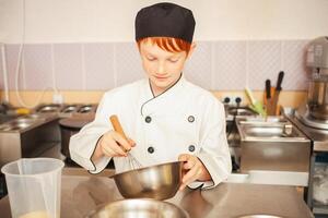 roodharig jongen in chef-kok kostuum kookt pannekoeken in keuken, kneedt deeg, assistent maakt ontbijt. ritme ei met vliegenmepper foto