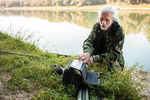 senior concept. een visser Aan rivier- vangsten roofzuchtig vis. nuttig hobby, mooi herfst, actief gezond levensstijl. verzamelt een zak foto