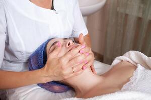 de schoonheidsspecialist massages de gezicht in de schoonheid salon foto