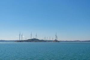 op het eiland midden in de zee staan veel windturbines onder de blauwe lucht foto