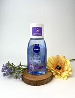 Jakarta, Indonesië - december 7e, 2023 - nivea blauw gekleurde verpakking fles micellair water Aan top van houten kustvaarder en geel Purper gekleurde bloem decoratie geïsoleerd Aan duidelijk wit achtergrond. foto