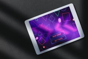 top visie foto van digitaal tablet met gaming menu Aan scherm over- donker oppervlak. spelen online concept met leeg ruimte voor tekst. online vermaak en gamificatie.